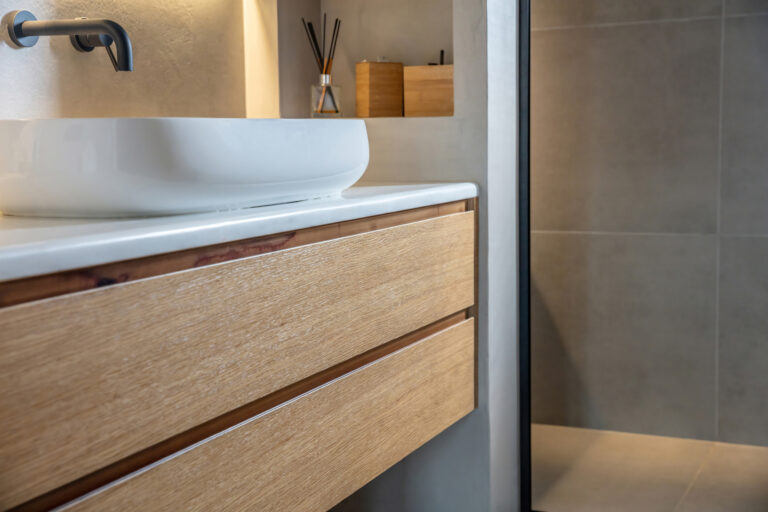Bathroom interior modern minimal design. Round sink basin on white marble counter, black taps on grey wall, Wooden storage drawer and decoration.